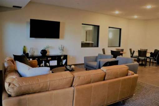 A living room with a brown couch and a flat screen TV mounted on the wall.