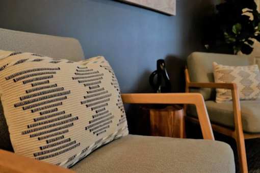 A couch with a patterned pillow sits in a room with a wooden side table.