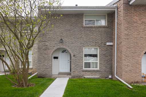 A brick building with a white door, windows, and a front lawn.