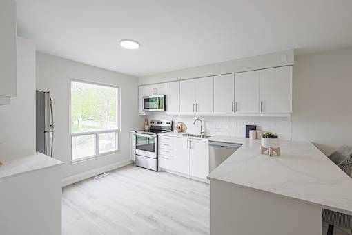 A white kitchen with a refrigerator, microwave, and cabinets.