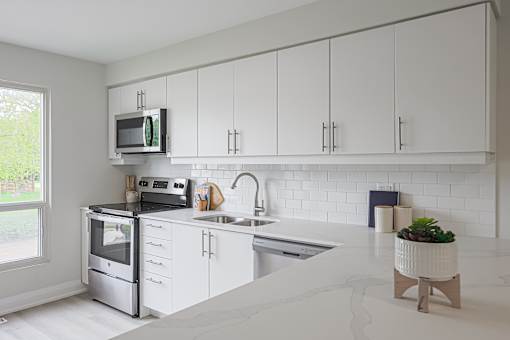 A kitchen with white cabinets and a marble countertop.