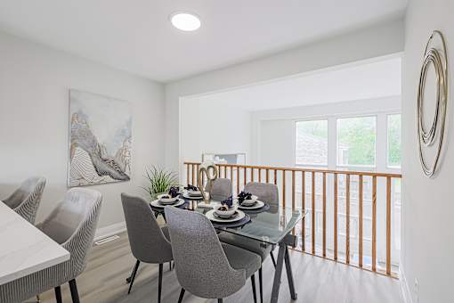 A dining room with a glass table and grey chairs.