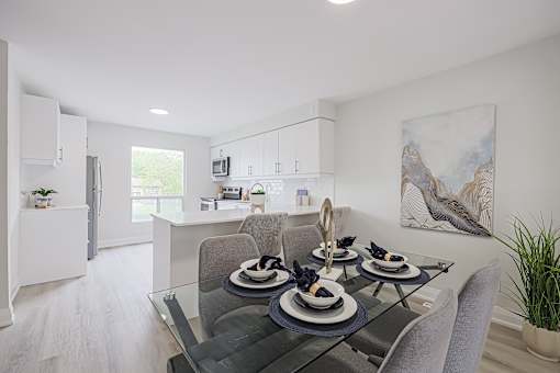 A modern dining room with a glass table and grey chairs.