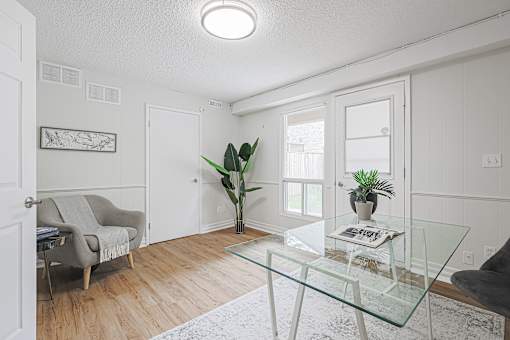 A living room with a glass table and a grey chair.