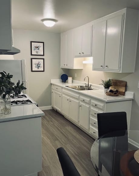 A kitchen with white cabinets and a black chair.
