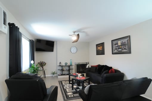 a living room with black furniture and a clock on the wall
