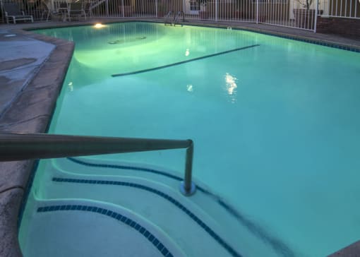 a large pool with a fence around it and a light shining on the water