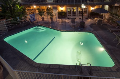 a pool is lit up at night in front of a building