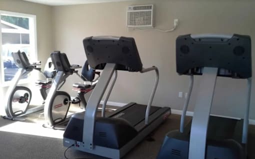 A room with a treadmill, elliptical trainer and a stationary bike.