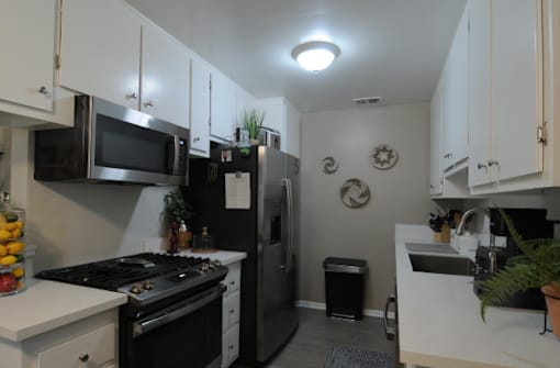 A kitchen with black appliances and white cabinets.