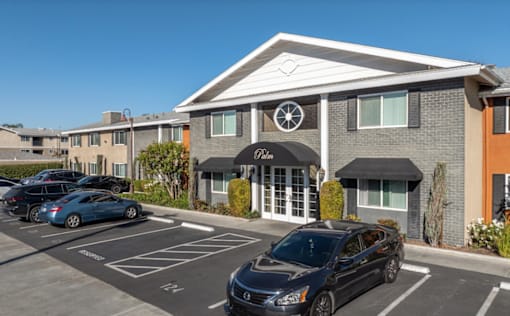 A black car is parked in a parking lot in front of a building with a sign that says "Park.".