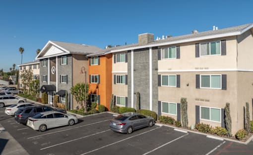 A parking lot with cars and apartment buildings.