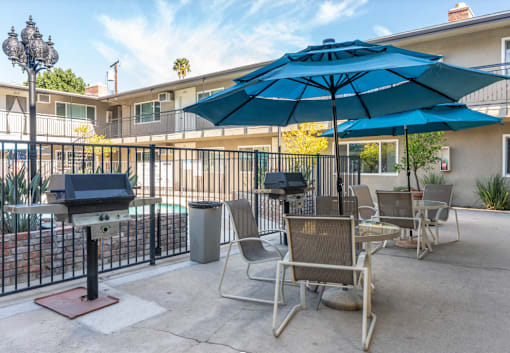 A patio with chairs and an umbrella is in front of a building.