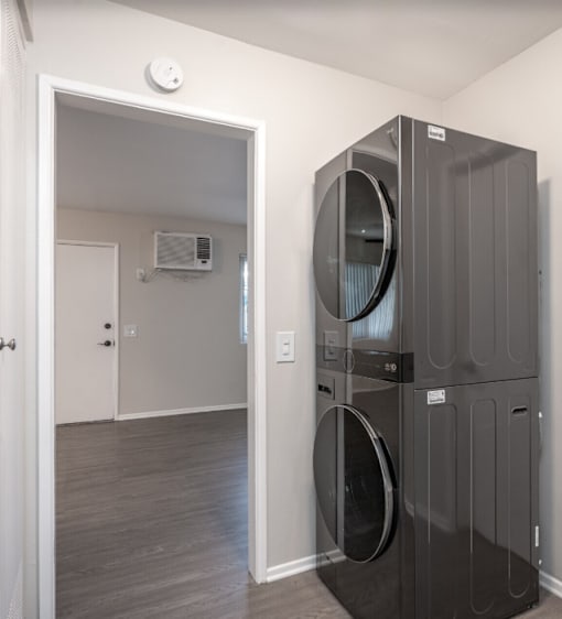A black front loading dryer and washer in a laundry room.