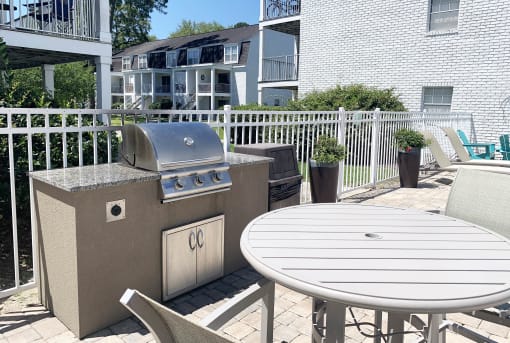 an outdoor kitchen with a grill and a table and chairs