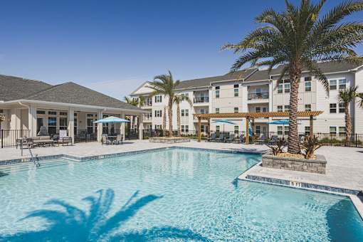 A large swimming pool in front of a building with palm trees.
