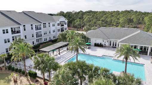 A large white building with a pool in front of it.