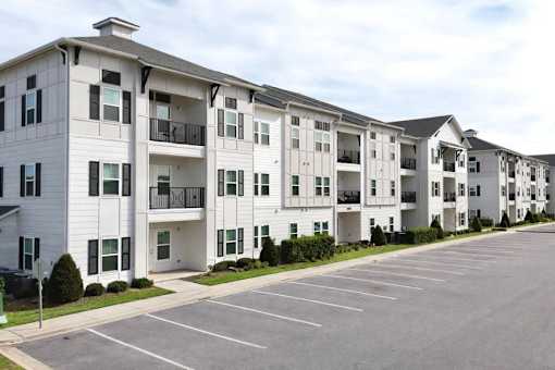 Apartment building with a parking lot in front.