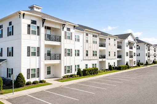 A row of white apartment buildings with black balconies and doors.