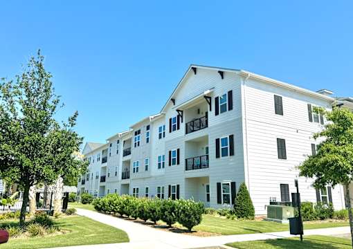 A white apartment building with a green lawn in front.