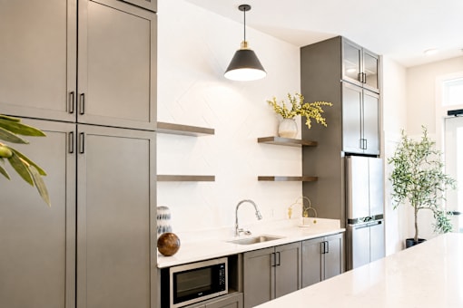 A modern kitchen with a white countertop and grey cabinets.