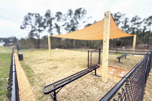 A baseball field with a canopy and benches.