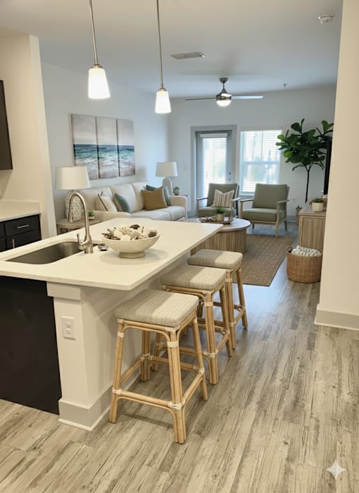 A kitchen with a white countertop and wooden bar stools.