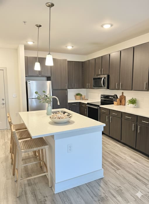 A modern kitchen with a white island and wooden chairs.