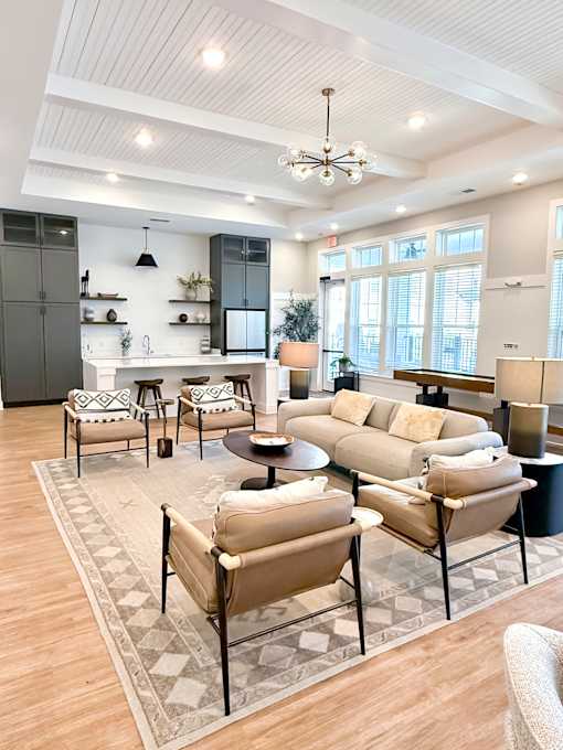 A living room with a beige sofa and a black and white rug.