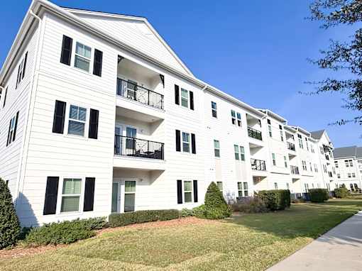 A white apartment building with black shutters and balconies.