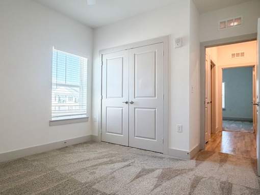 A room with a white door and a window with blinds.