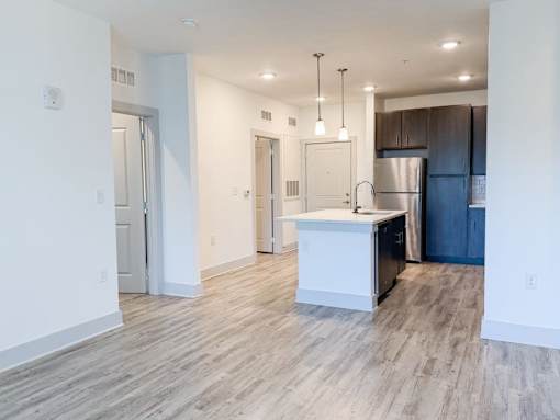 A kitchen with a refrigerator, sink, and cabinets.