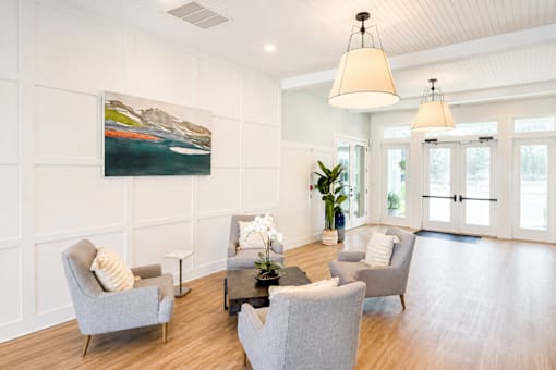 A living room with a grey couch and a painting on the wall.