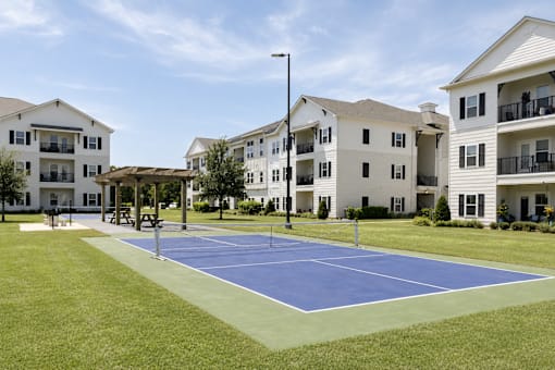 A tennis court in front of apartment buildings.