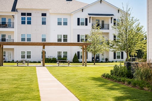 A white building with a balcony and a walkway in front.