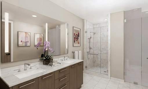 A bathroom with a large mirror, two sinks, and a walk-in shower.
