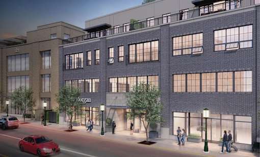 A red car is driving down a street past a building with a sign that says Morgan.