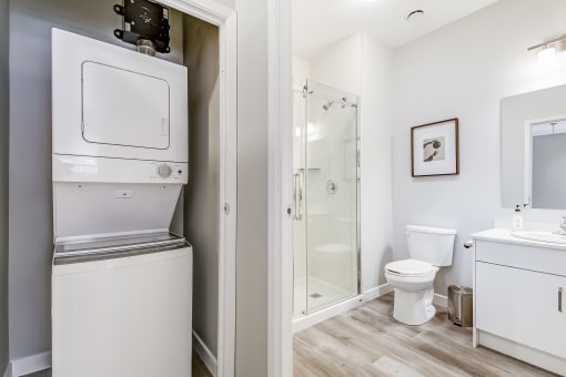 stacked washer/dryer and bathroom with walk in shower
