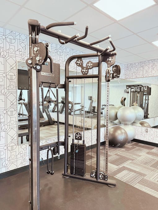 A gym with a weight machine in the foreground.