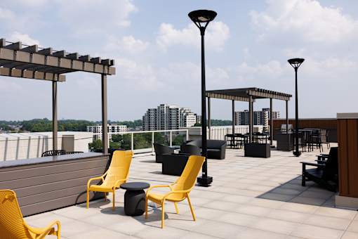 A rooftop patio with yellow chairs and tablesat 1600 Hyde Park Village Apartments, London