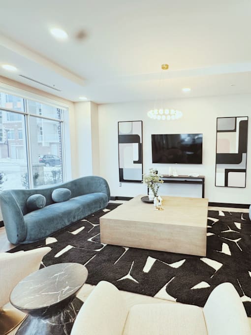 A living room with a blue couch, a wooden coffee table, and a black and white rug.