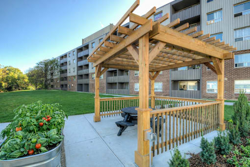A wooden pergola is in front of a building with a bench underneath it  at Platts Crossing, London, ON, N6H 4P4