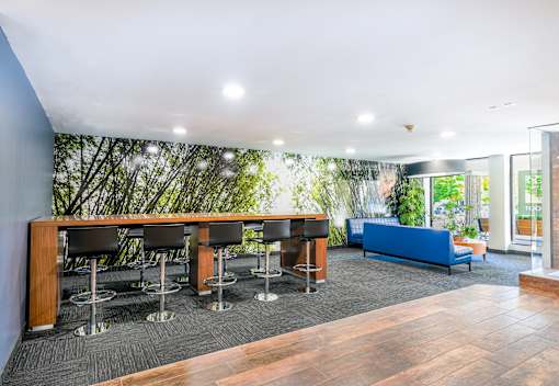 A room with a long table and chairs with a green planted wall behind it.