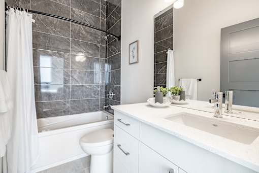 A white bathroom with a marble tile wall and a white toilet.