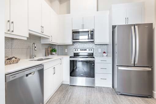 A modern kitchen with white cabinets and stainless steel appliances.