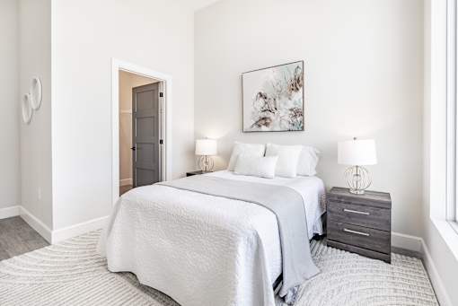 A bedroom with two beds and a nightstand with lamps.