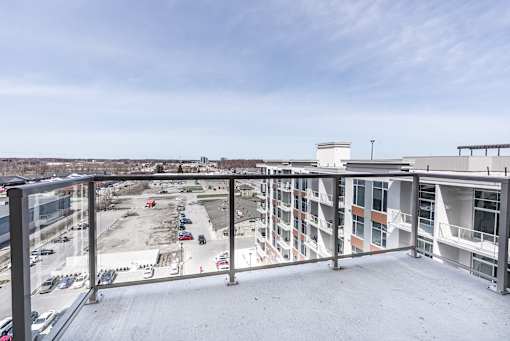 A view from a balcony overlooking a parking lot and buildings.