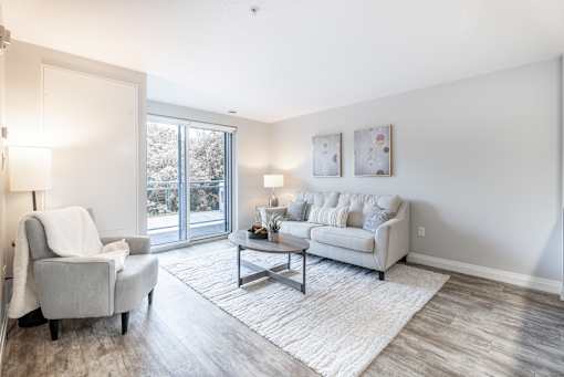 A living room with a grey couch, a white chair, and a coffee table.