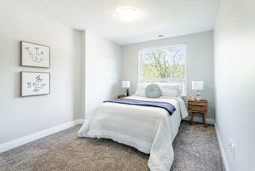 A bedroom with a large bed and two pictures on the wall.