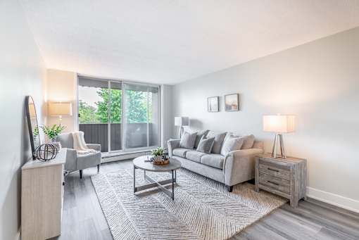 A living room with a grey couch, a coffee table, and a lamp  at Platts Crossing, London, ON, N6H 4P4